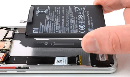 Extracción de la batería de un celular Xiaomi abierto sobre la mesa de trabajo