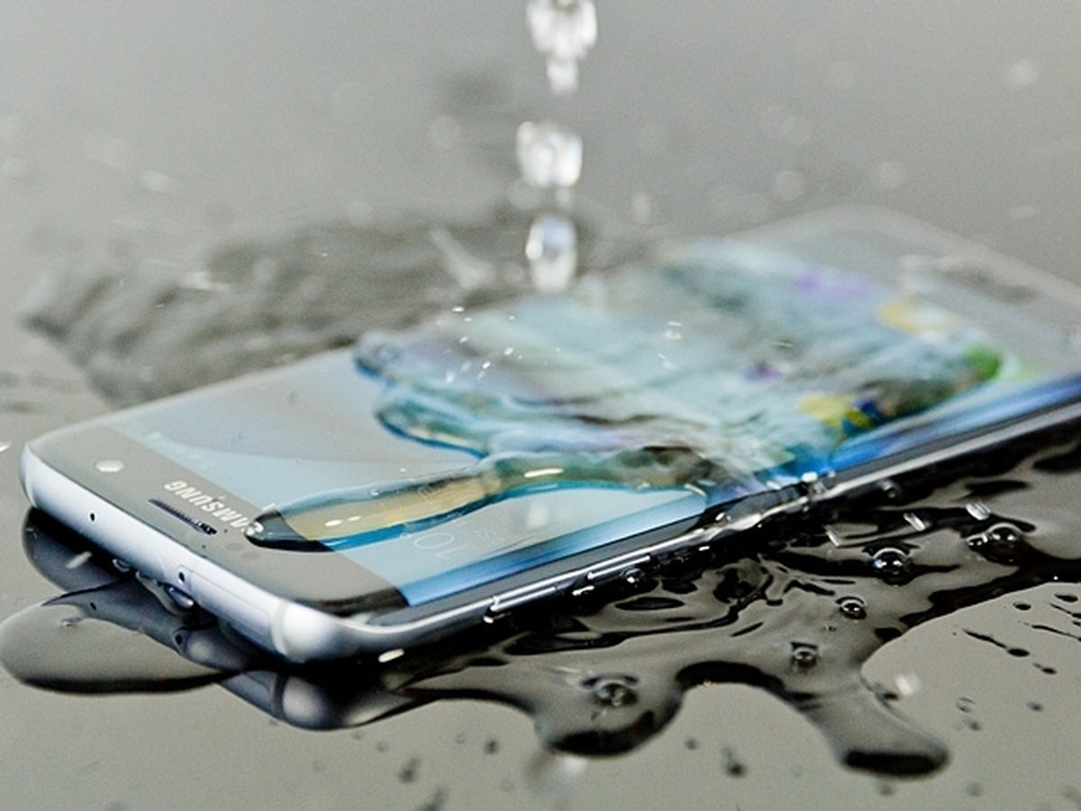 Celular Samsung sobre una superficie mojada mientras le cae agua encima